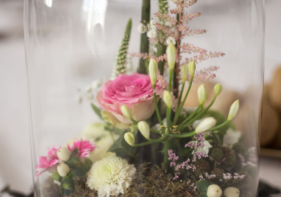 Bloemencompositie onder glazen koepel met roze roos en astilbe 